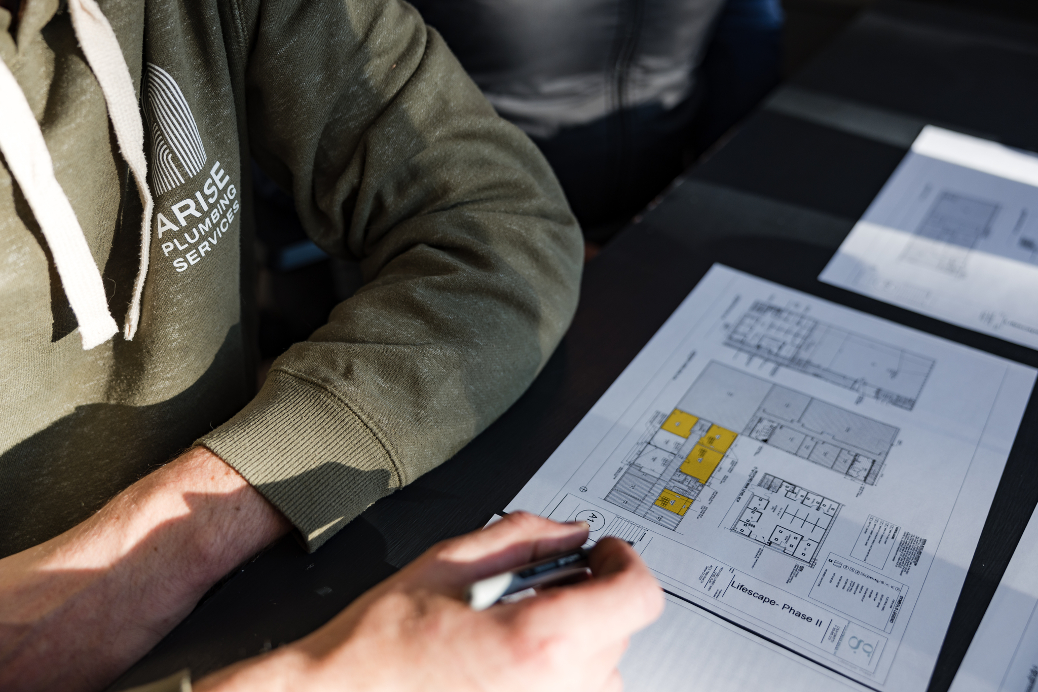Arise plumber reviewing a plumbing plan on paper