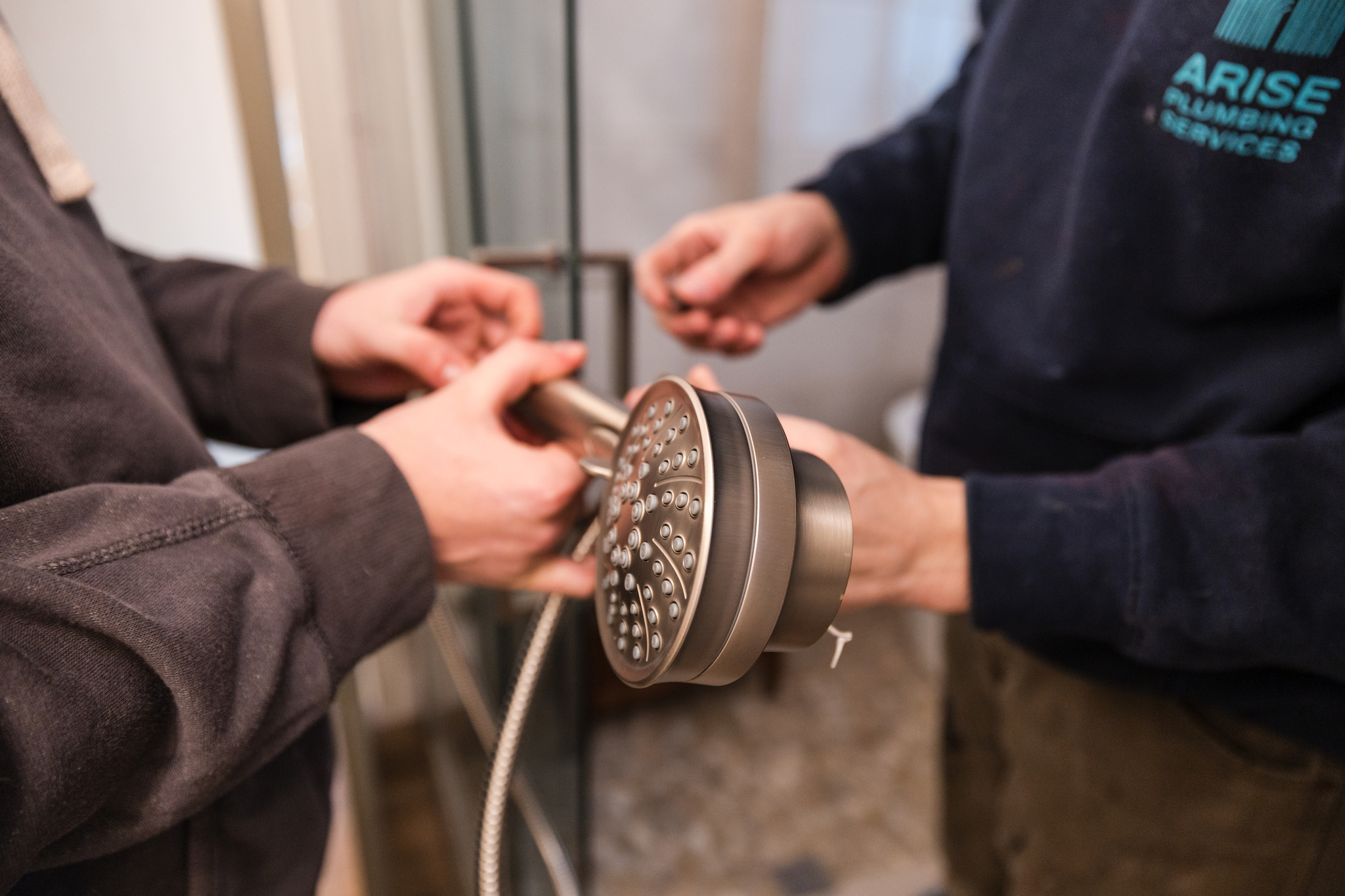 Two plumbers inspecting a shower head fitting